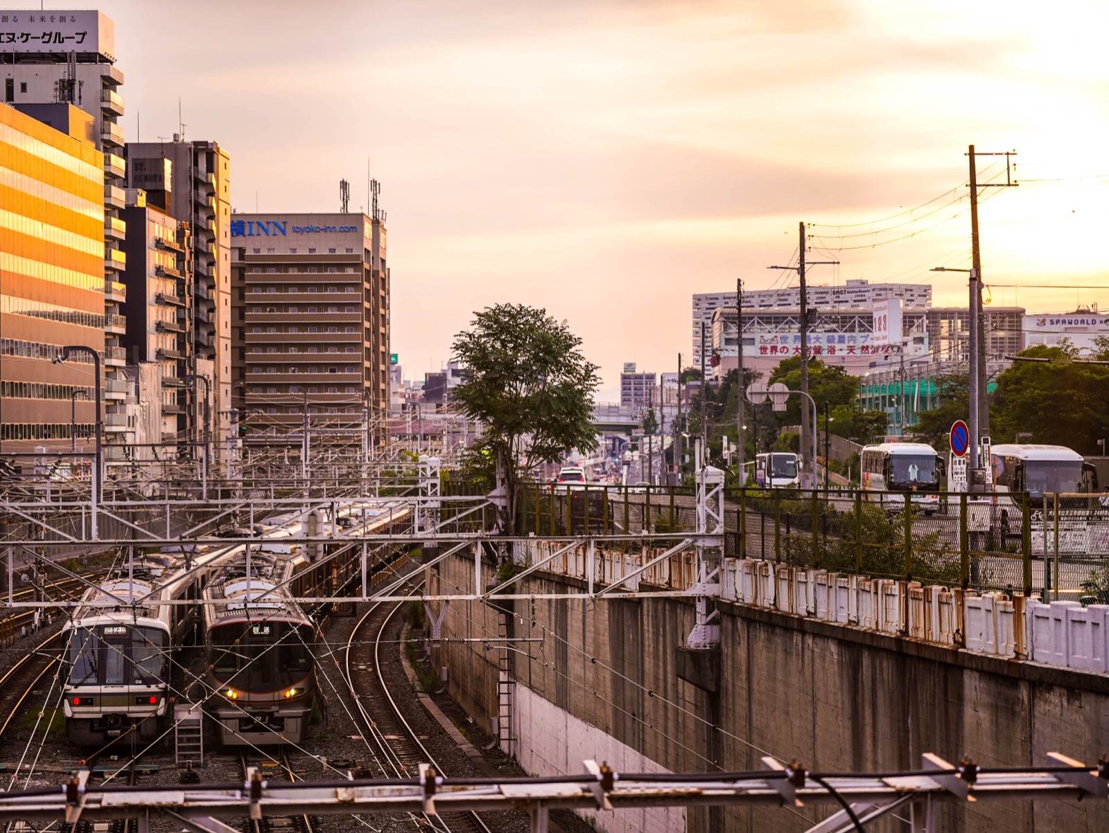 Commuter trains pass city buildings in warm evening light.