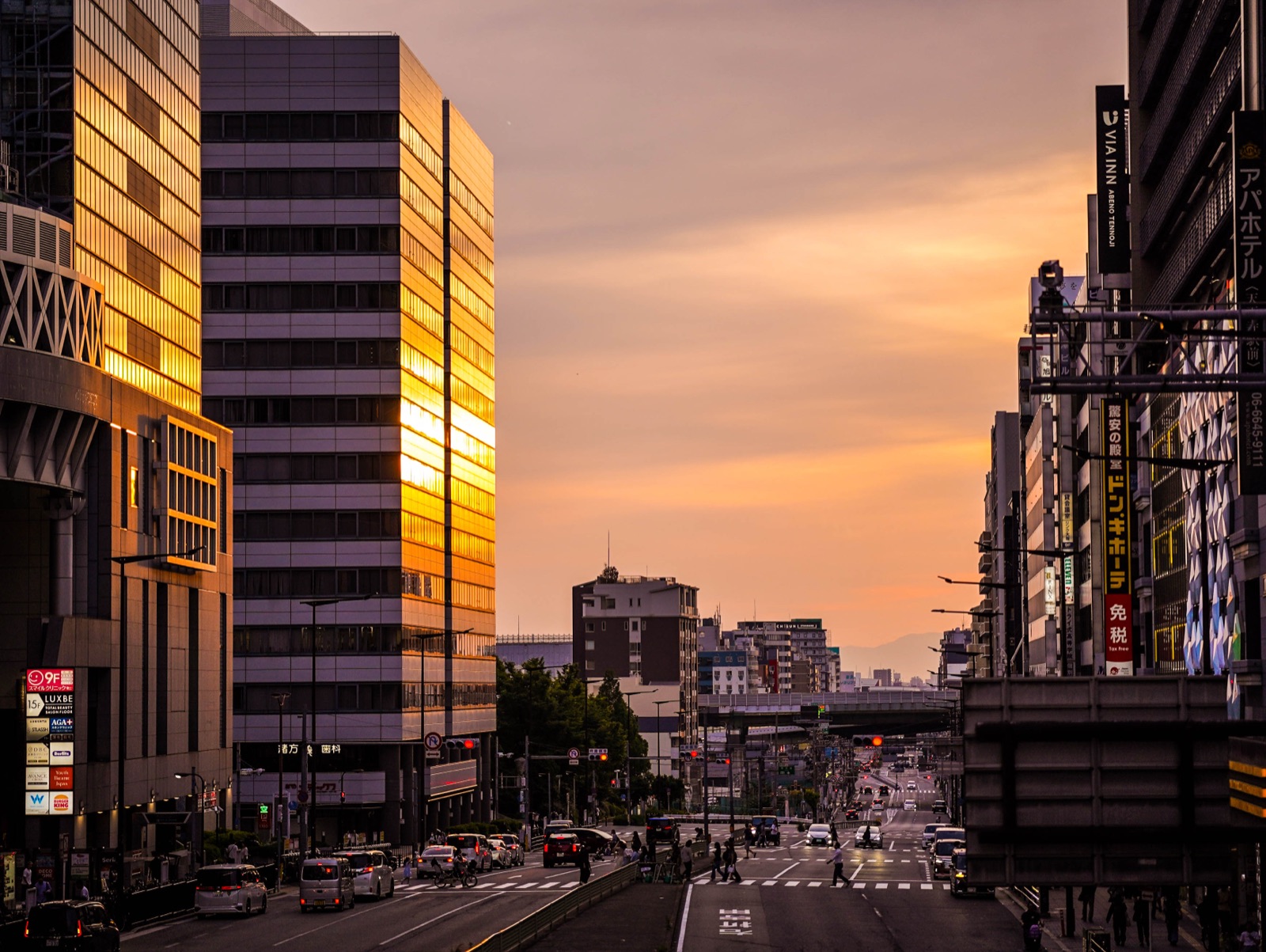 Tall city buildings frame an avenue in golden sunset light.