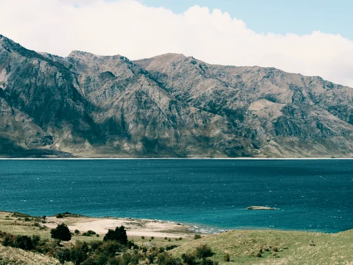 Turquoise water and a rocky shore below rugged mountains.