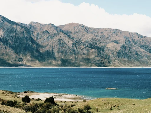 Turquoise water and a rocky shore below rugged mountains.