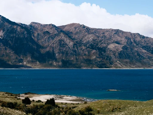 Turquoise water and a rocky shore below rugged mountains.