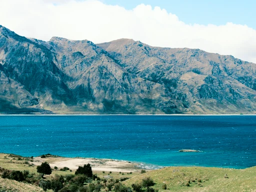 Turquoise water and a rocky shore below rugged mountains.