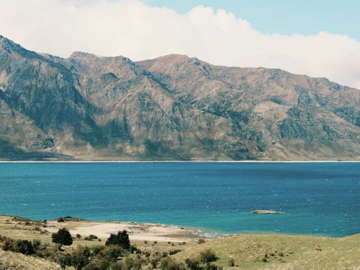 Turquoise water and a rocky shore below rugged mountains.