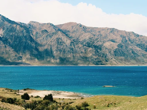 Turquoise water and a rocky shore below rugged mountains.