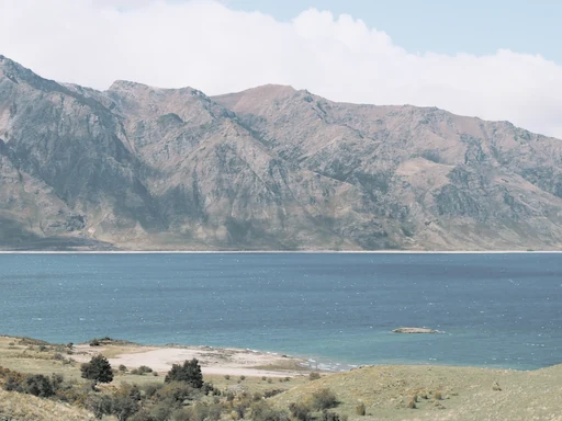 Turquoise water and a rocky shore below rugged mountains.