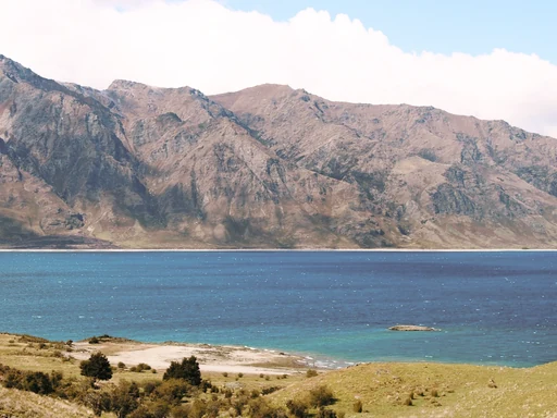 Turquoise water and a rocky shore below rugged mountains.